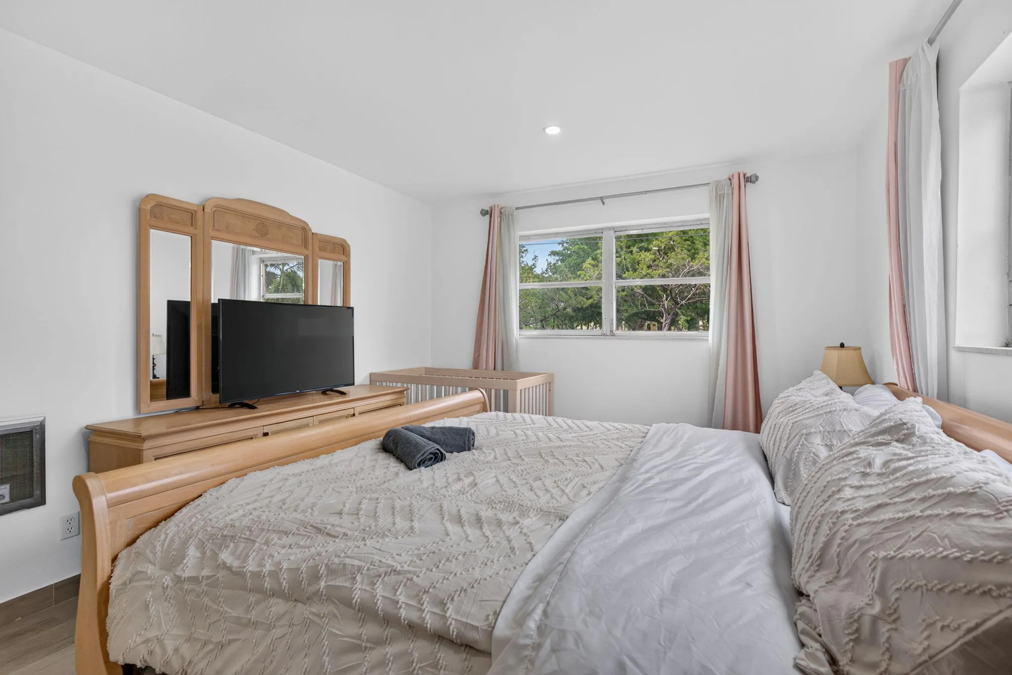 Primary Bedroom with Mounted TV, Dresser and Generous Natural Light