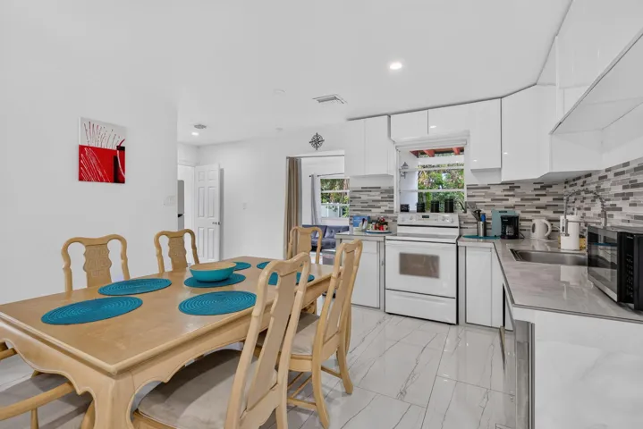 Renovated Open-Concept Kitchen with White Shaker Cabinetry and Tile Backsplash