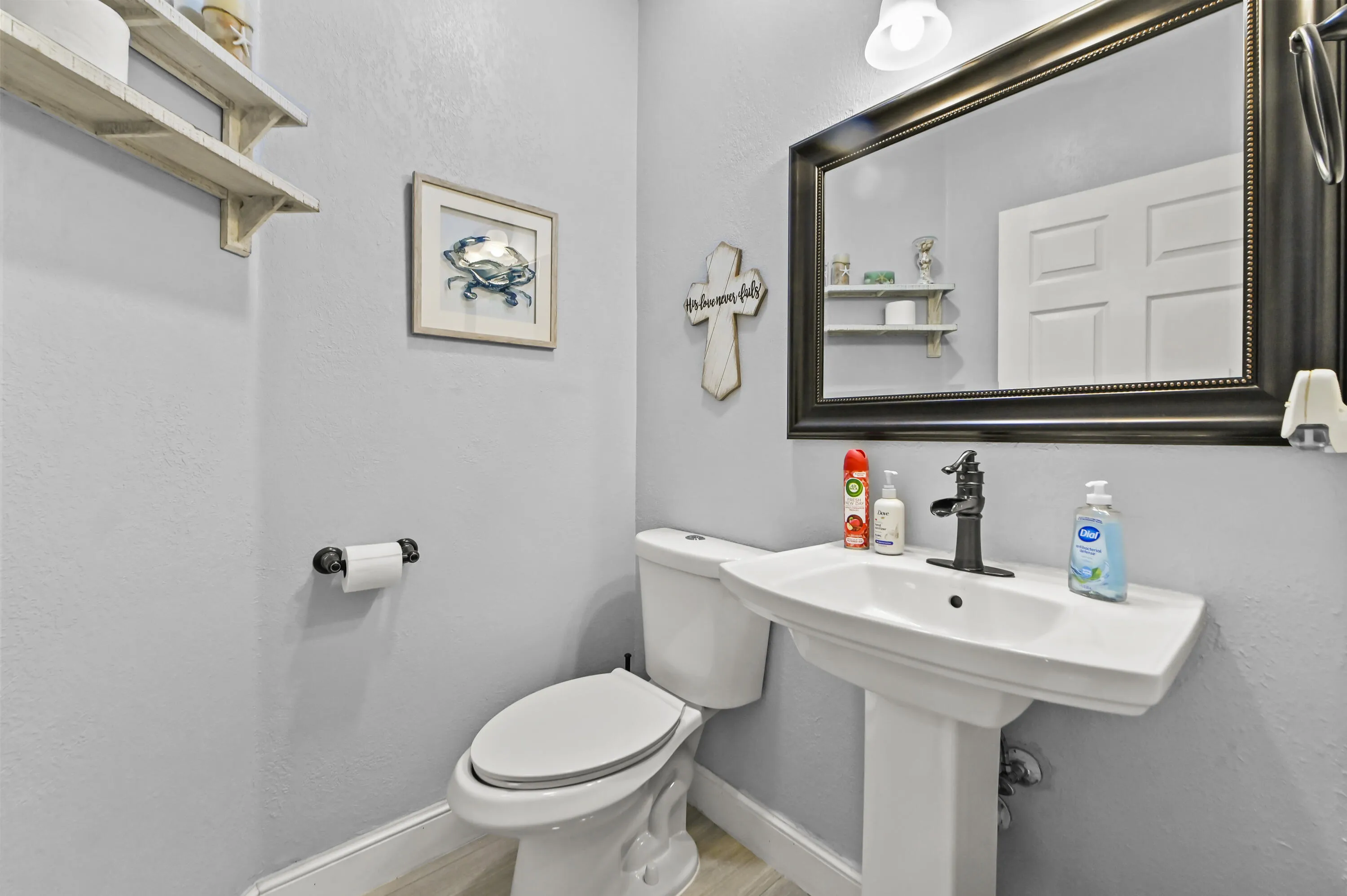 Pedestal sink with a single-handle faucet, wall-mounted mirror, and overhead lighting