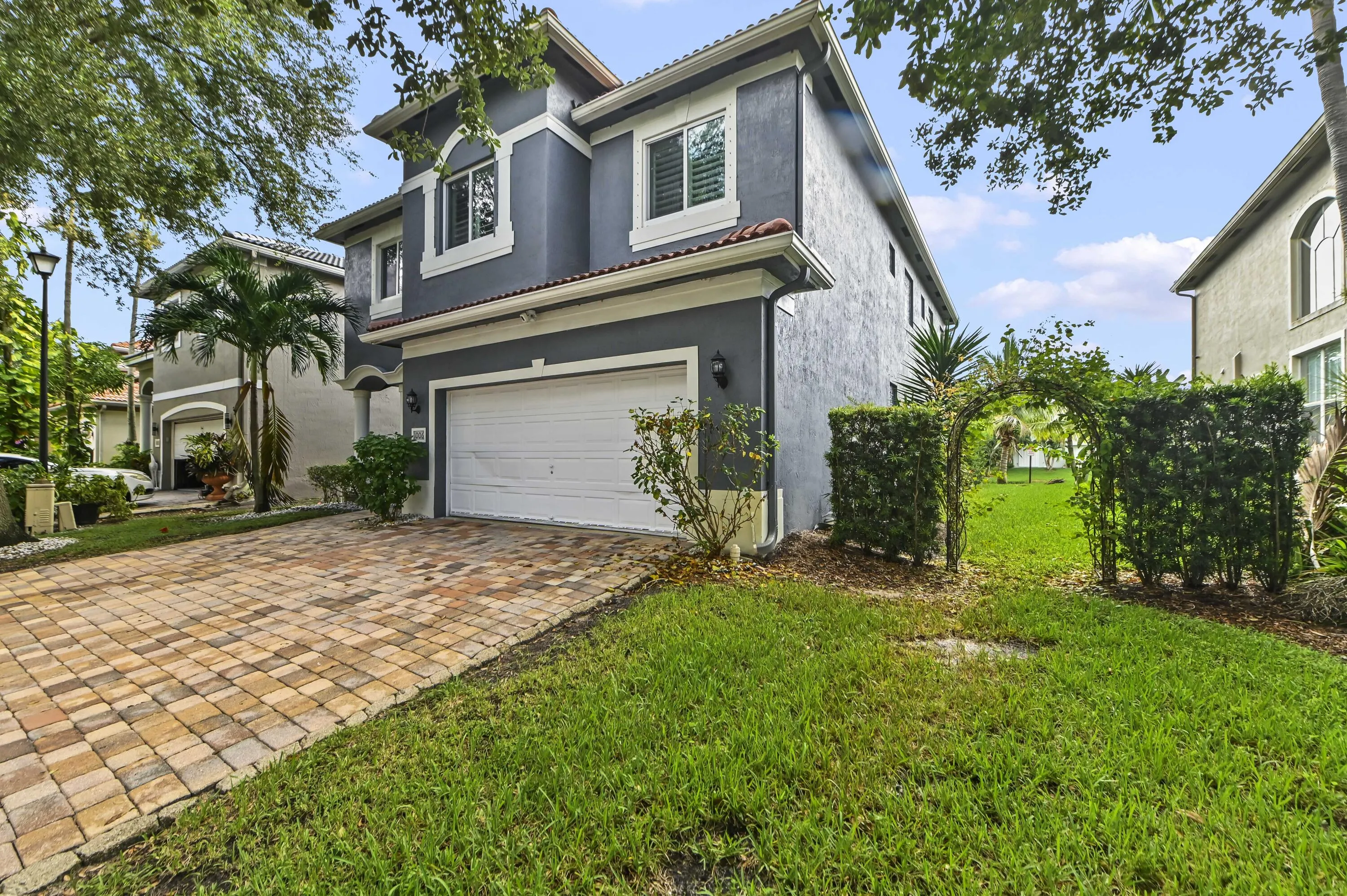 Two-story stucco exterior with white trim, a single garage, and a paver driveway