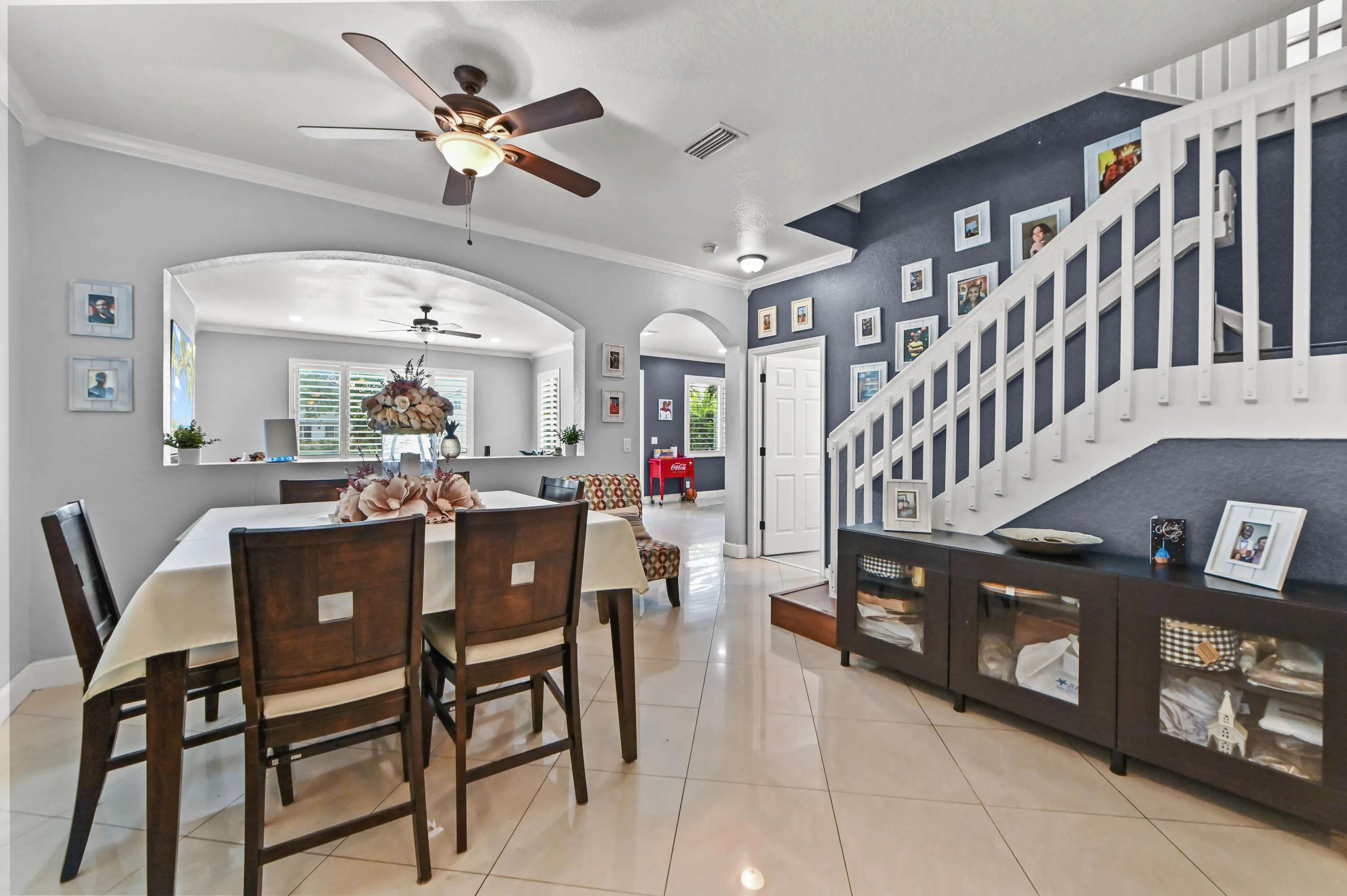 Tile flooring, arched pass-through window, ceiling fan, white balustrade, and built-in cabinetry