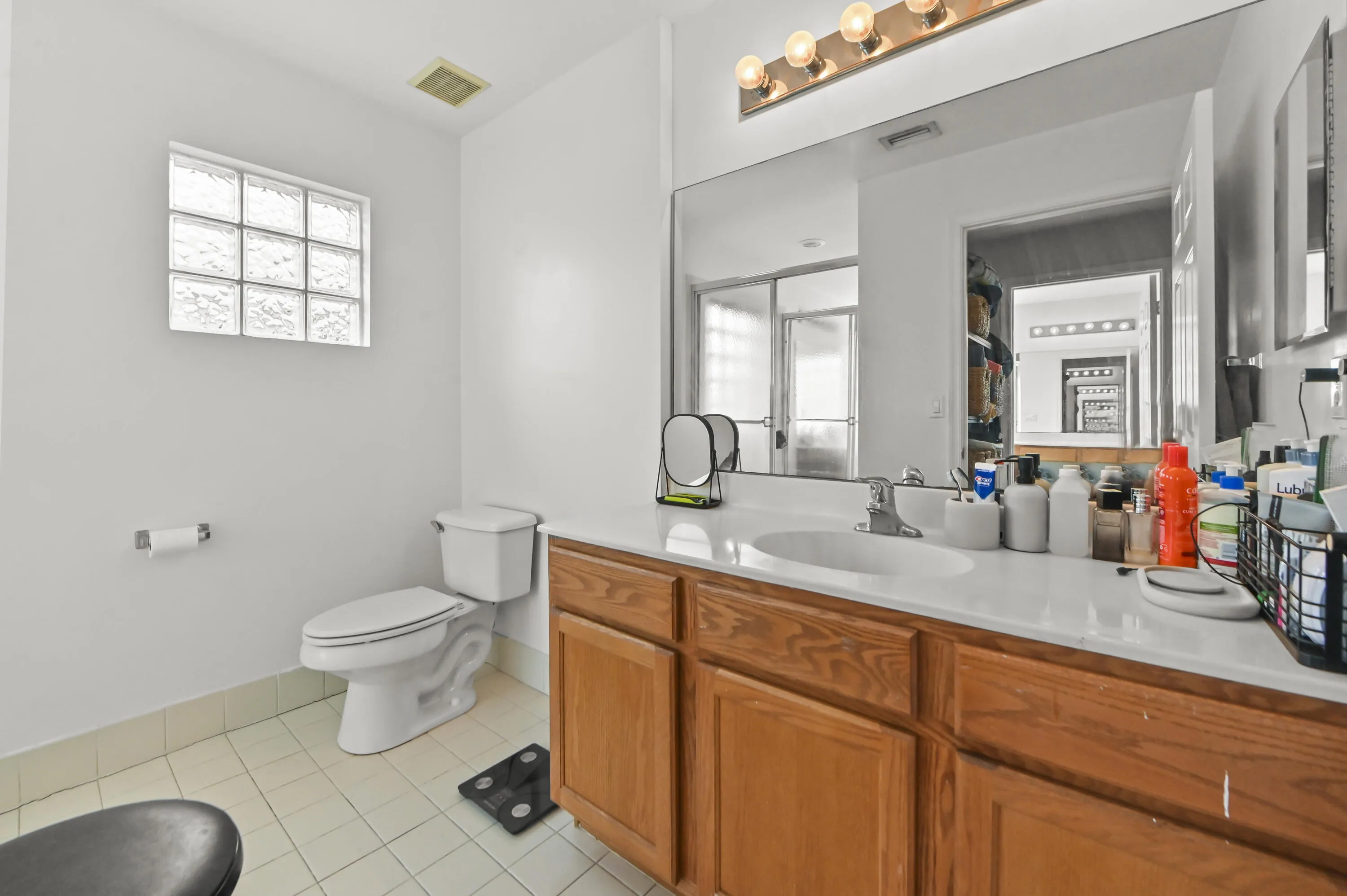 Single vanity with wood-finish cabinetry, integrated sink, and extended mirror