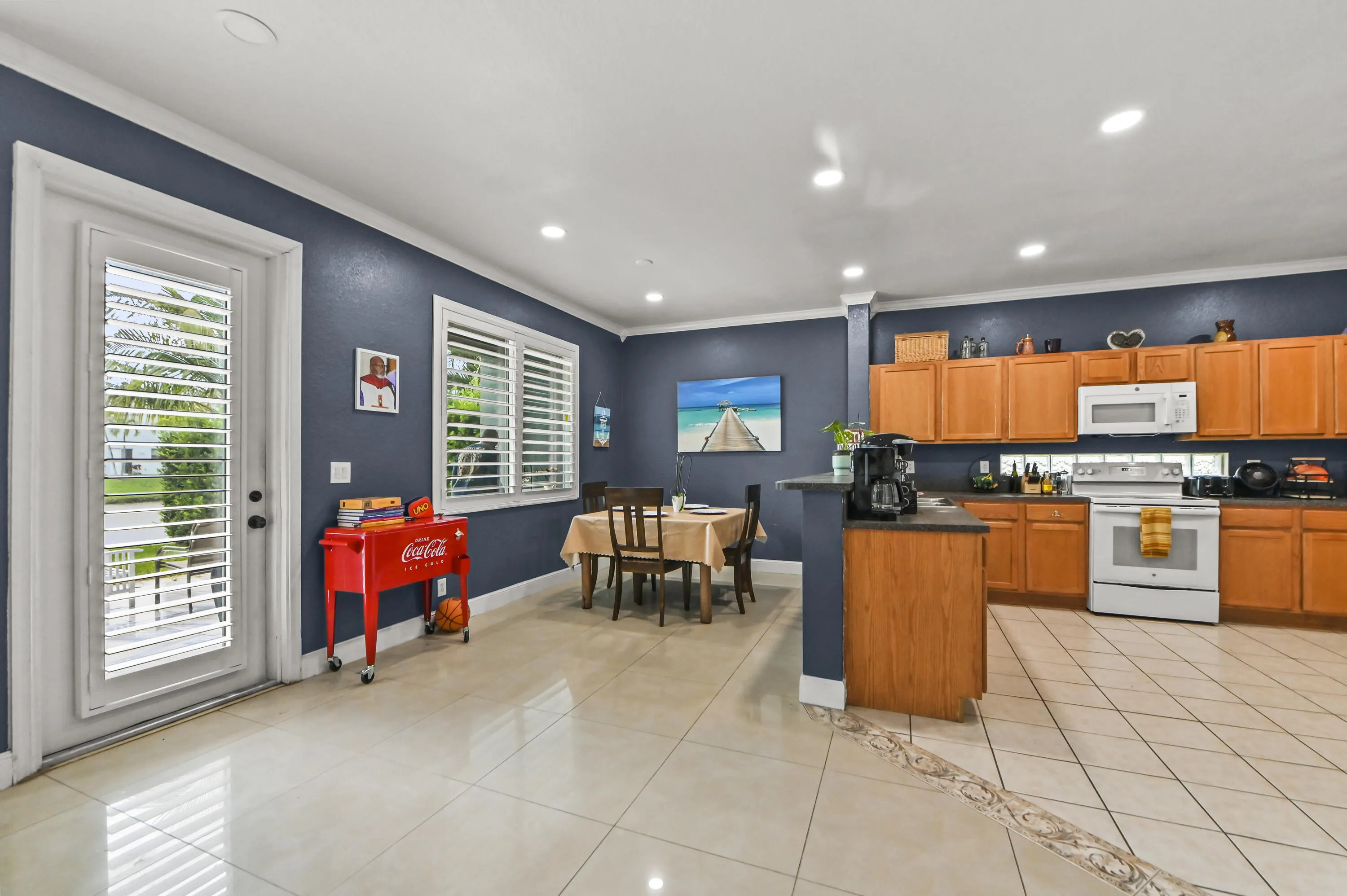 Spacious kitchen featuring light wood cabinetry, white appliances, and a breakfast bar
