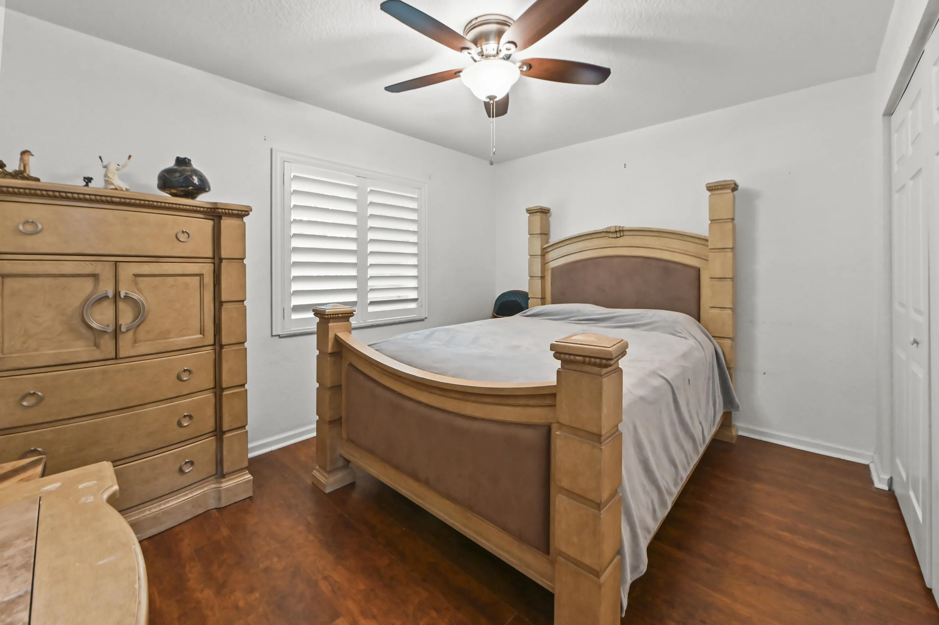 Wood-finish flooring, ceiling fan with integrated lighting, and white plantation shutters