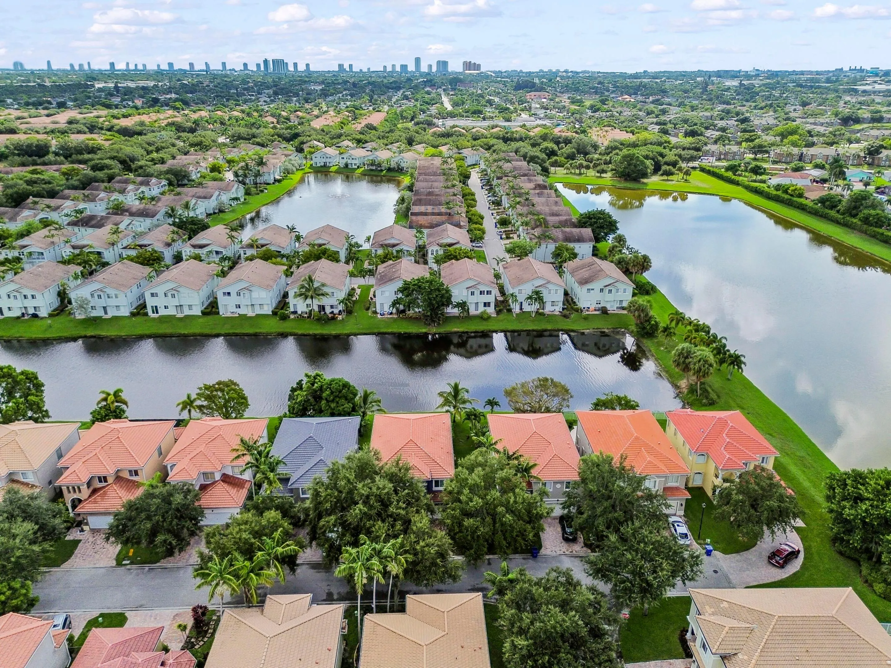 Community featuring multiple bodies of water, extensive green spaces, and a variety of residential structures with distinct architectural styles