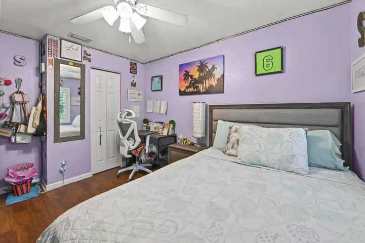 Spacious bedroom featuring a wood-finish floor, purple accent walls, and a gray upholstered bed frame