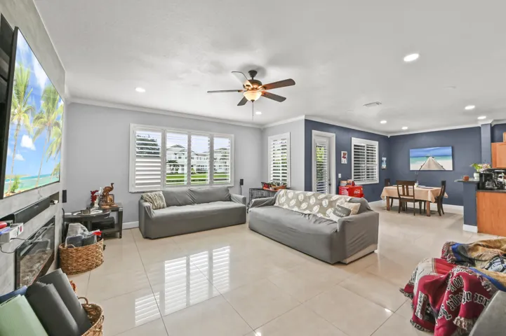 Spacious open-concept living area featuring large format tile flooring, crown molding, and recessed lighting