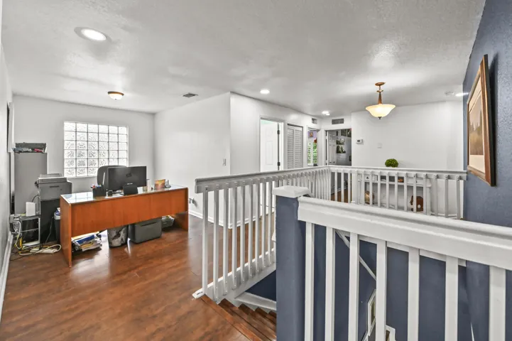 Spacious open loft area with wood-finish flooring, recessed lighting, and a glass block window