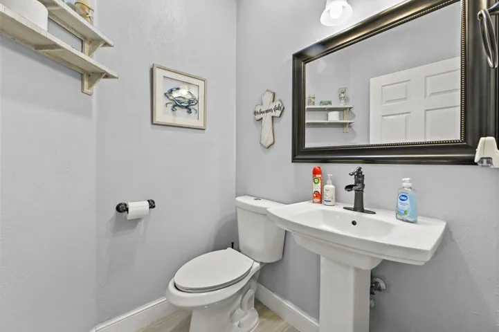 Pedestal sink with a single-handle faucet, wall-mounted mirror, and overhead lighting