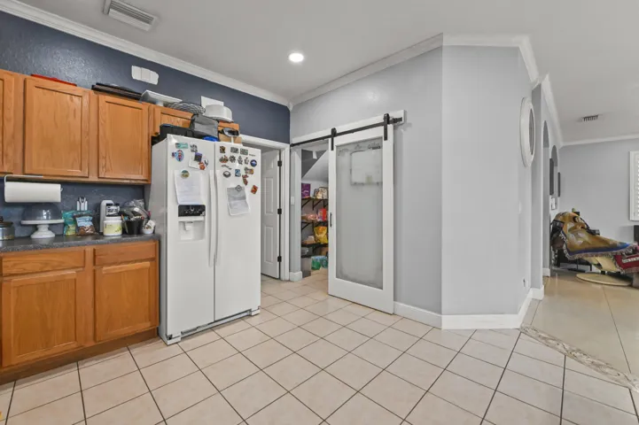 Kitchen featuring wood-finish cabinetry, tile flooring, recessed lighting, and a barn-style door