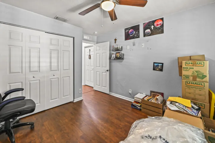 Wood-finish flooring, bi-fold closet doors, ceiling fan with integrated lighting, and a paneled interior door