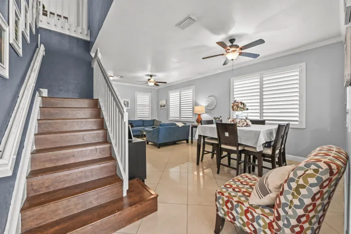 Wood-finish staircase with white railings, tile flooring, and multiple ceiling fans