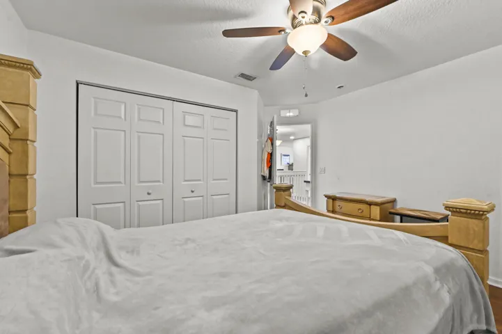 Ceiling fan with light fixture, double bi-fold closet doors, white wall finishes, wood-finish flooring
