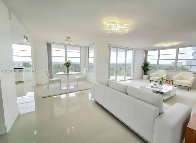 Open-concept interior featuring large-format tile flooring, oversized windows, glass sliding door access to a balcony, and contemporary multi-ring LED flush-mount lighting