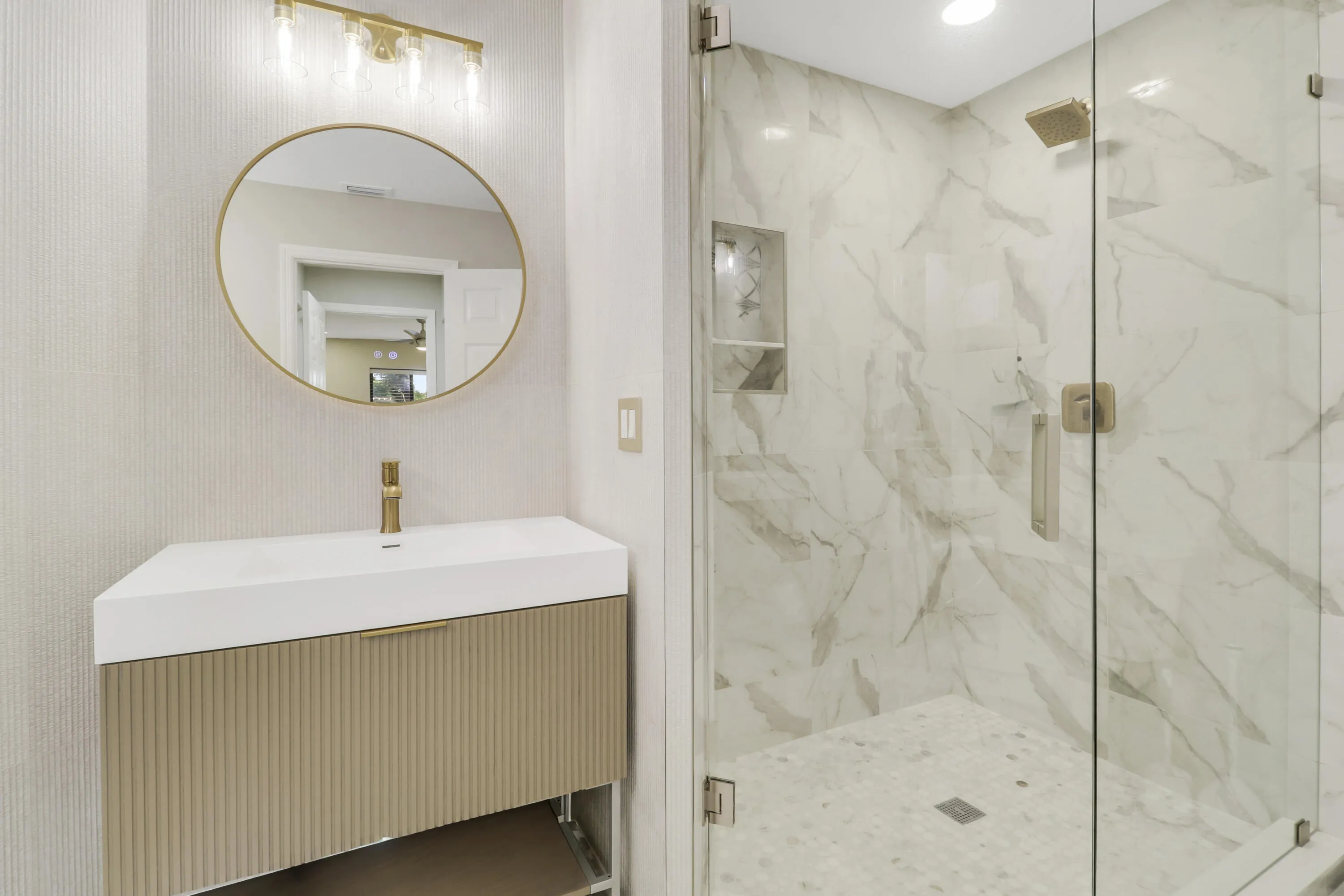 Walk-in shower with full-height marble-look tile, glass enclosure, and a built-in niche