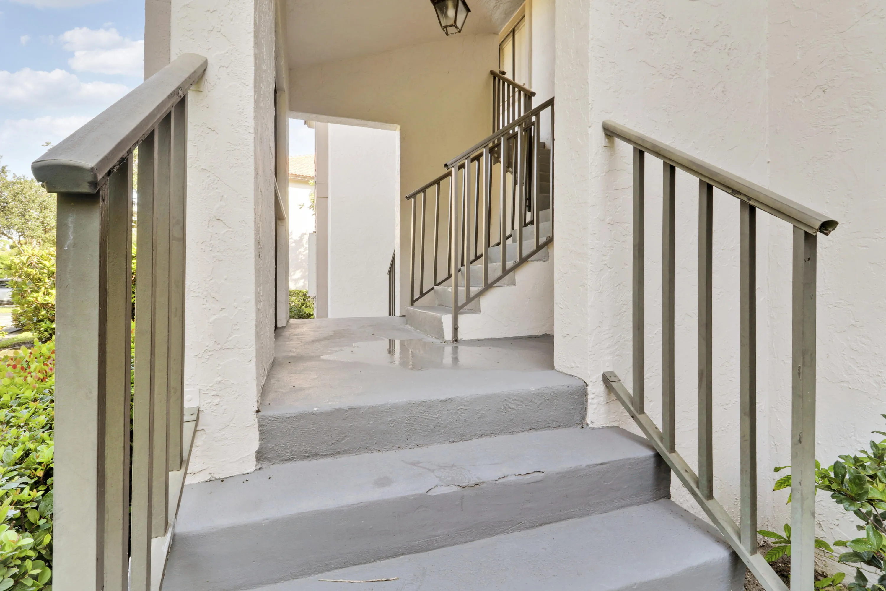 Staircase entry with painted concrete treads and painted metal handrails