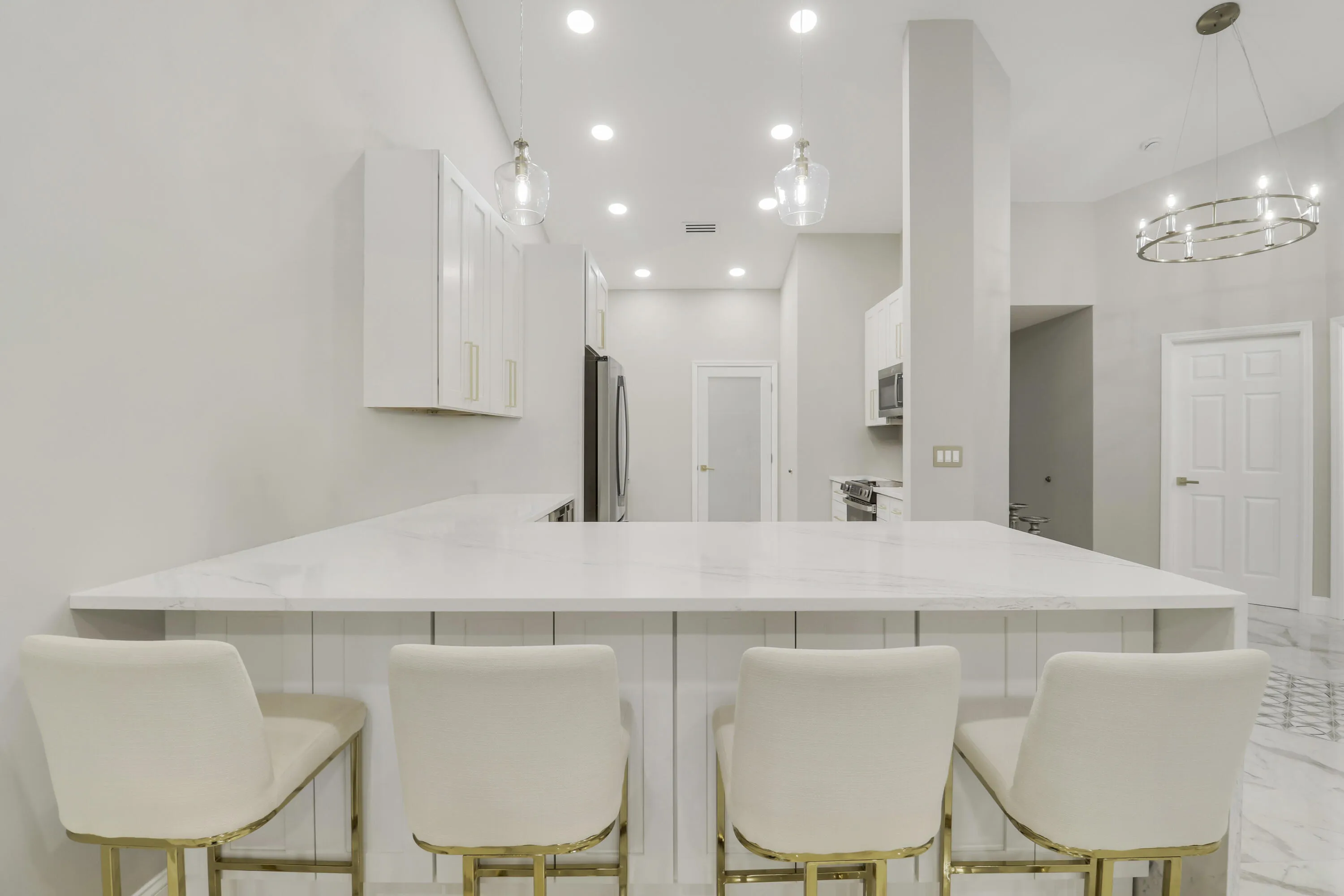 Expansive kitchen island with a light-toned countertop, recessed lighting, and pendant fixtures