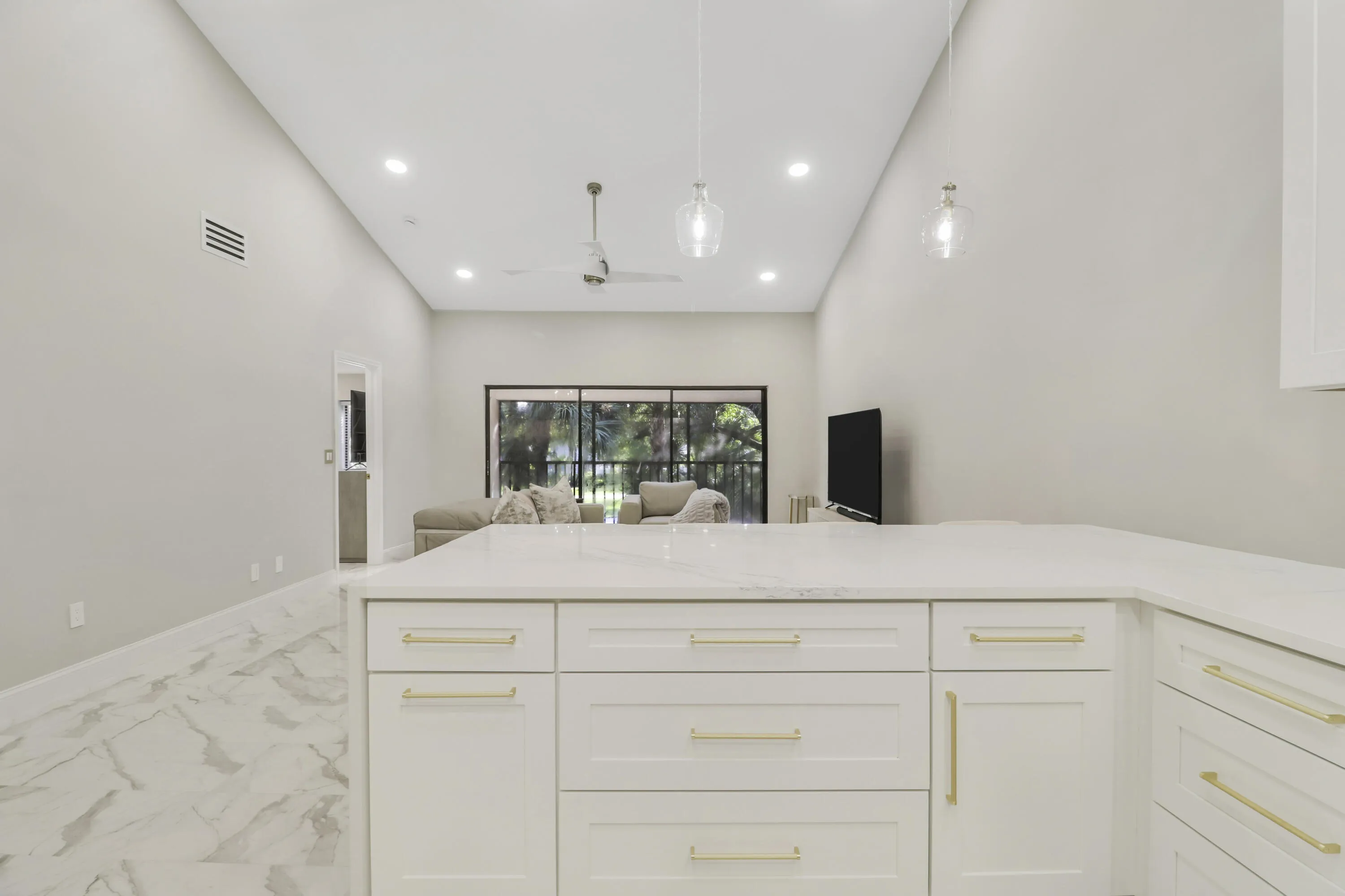 White cabinetry with gold-tone hardware, white countertop, and marble-look flooring