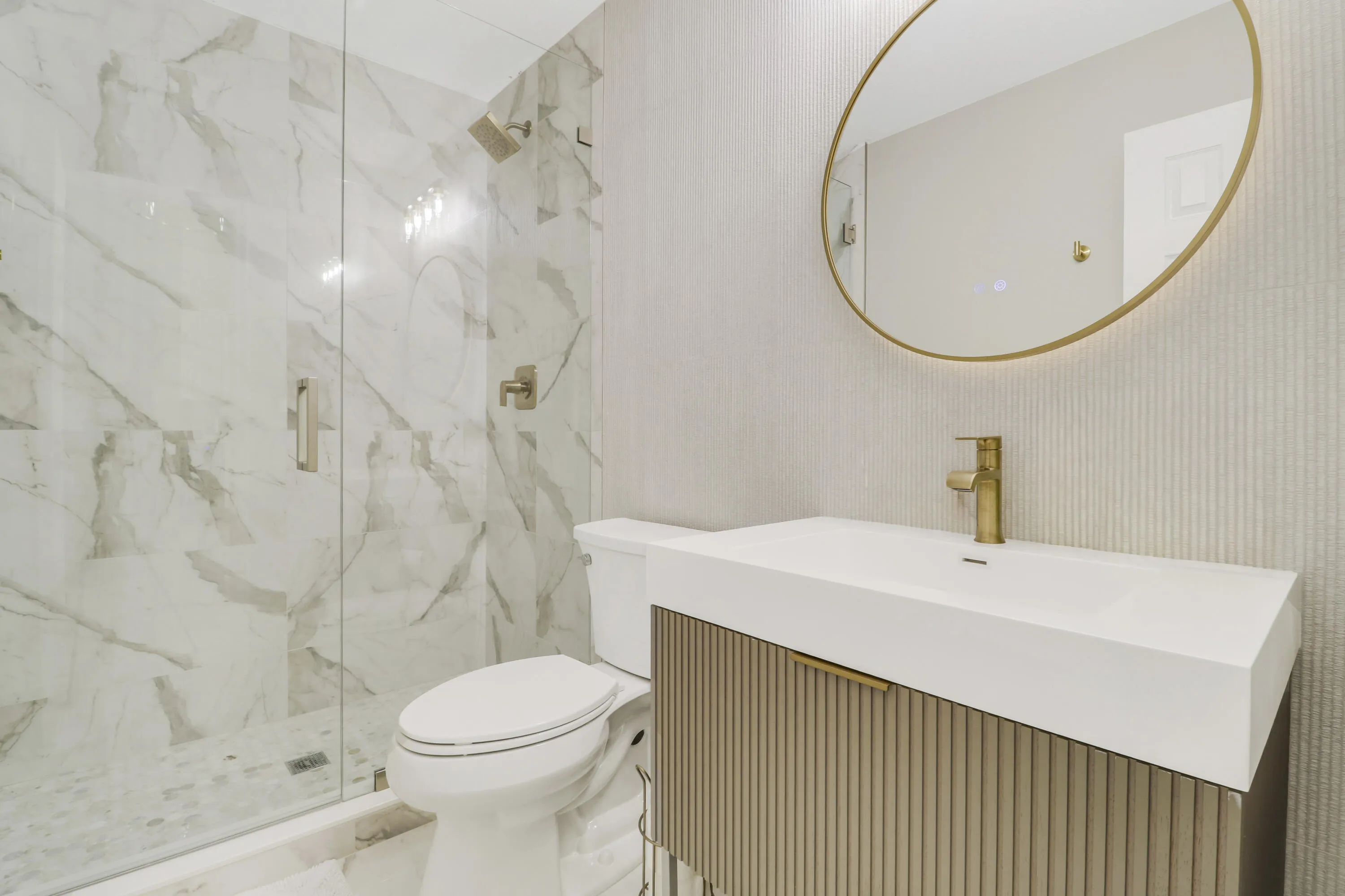Walk-in shower with clear glass enclosure and marble-style tile