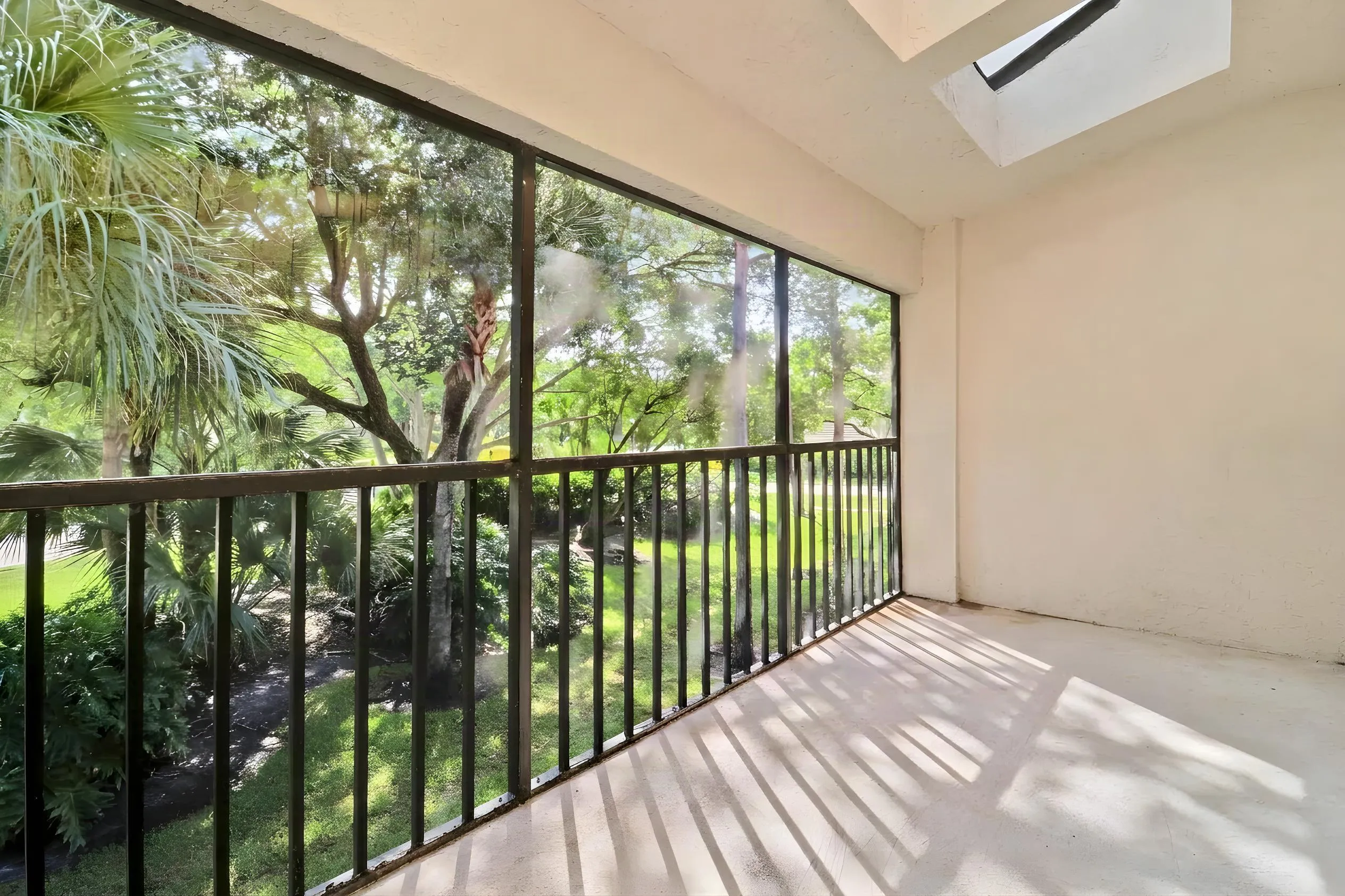 Screened-in balcony with a black metal railing and a skylight