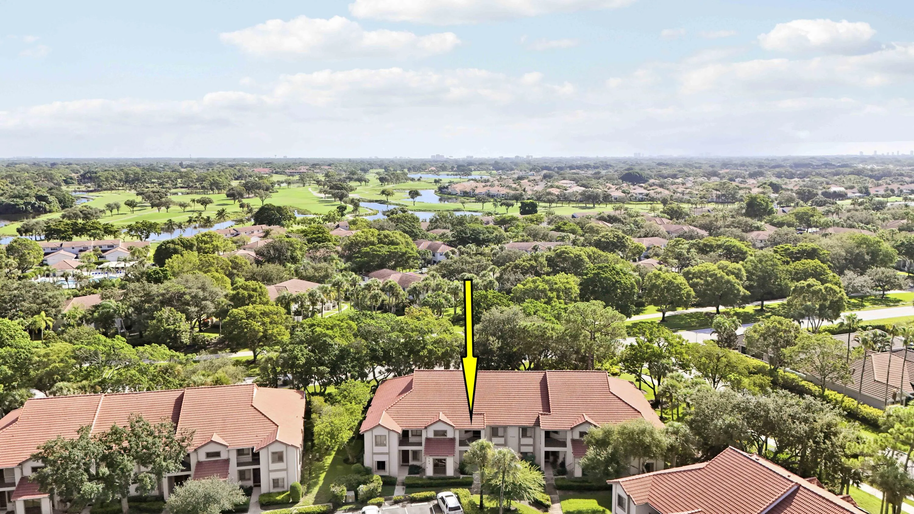 Townhome-style residences with terra cotta tile roofs situated within a lush, treed community