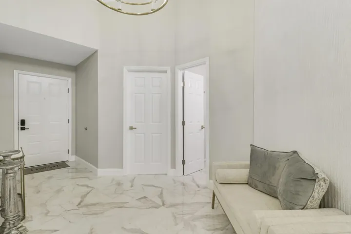 High ceilings with a decorative chandelier, white paneled doors, and large-format tile flooring