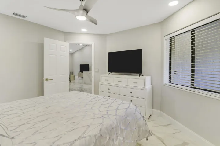 Recessed ceiling lighting, modern ceiling fan, paneled interior door, window with horizontal blinds, and large format floor tiling
