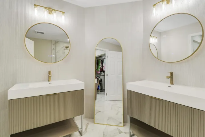 Dual vanity sinks with gold-finish fixtures and round mirrors