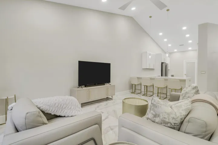 Vaulted ceiling, recessed lighting, tile flooring, modern kitchen island, and stainless steel refrigerator