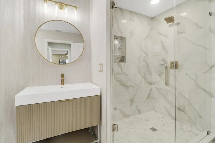 Walk-in shower with full-height marble-look tile, glass enclosure, and a built-in niche