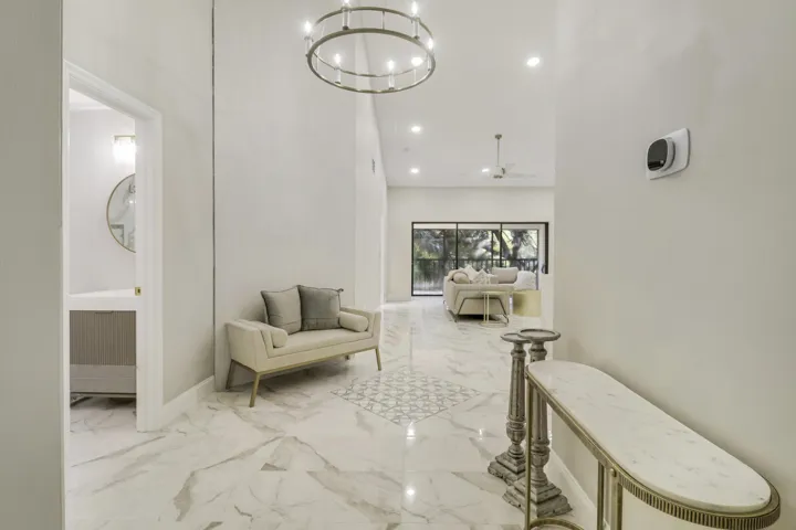 Vaulted ceiling with a chandelier, tile flooring, recessed lighting, and a partial bathroom with a wall-mounted vanity