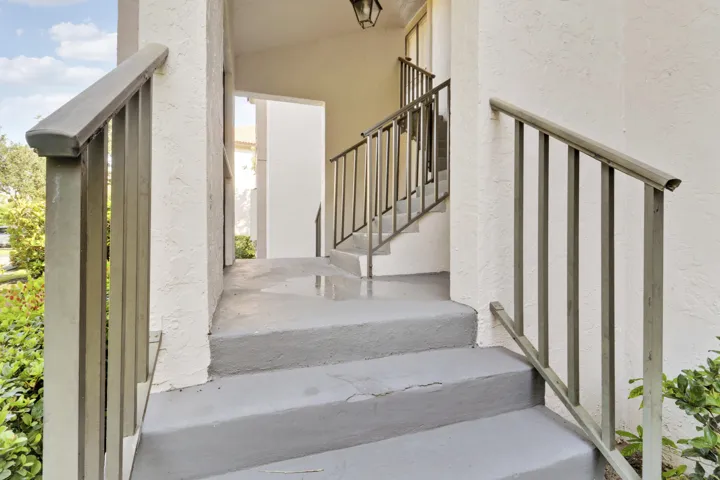 Staircase entry with painted concrete treads and painted metal handrails