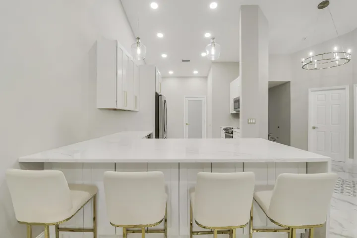Expansive kitchen island with a light-toned countertop, recessed lighting, and pendant fixtures