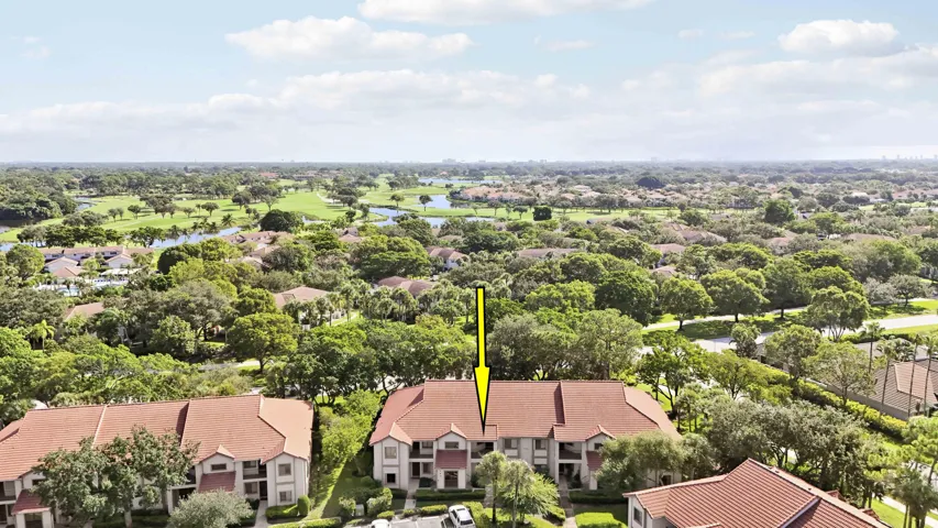 Townhome-style residences with terra cotta tile roofs situated within a lush, treed community
