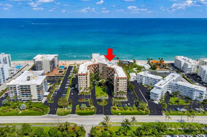 Beachfront multi-story building featuring a U-shaped design, a central green space, and direct beach access