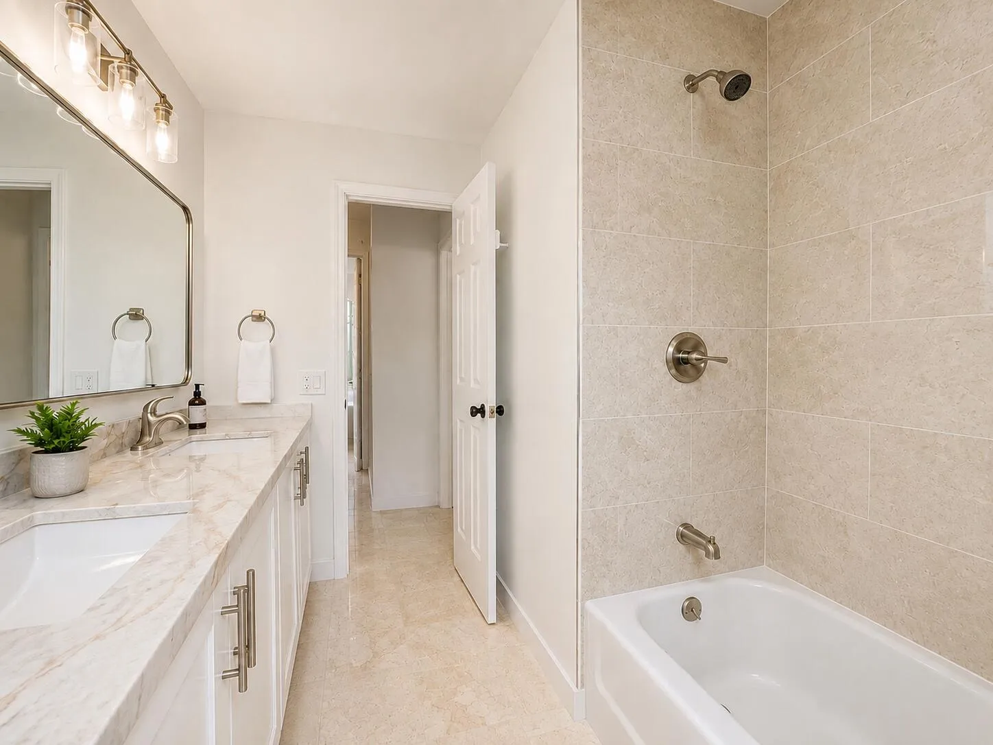 White vanity with brushed nickel hardware, a rectangular undermount sink, and a stone countertop
