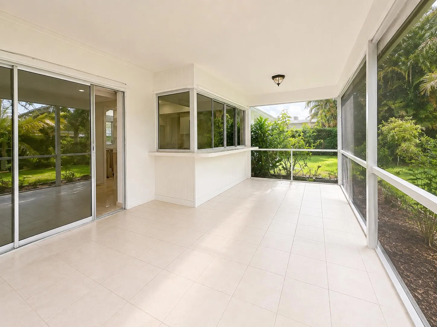 Screened patio featuring tile flooring, a built-in counter, and sliding glass door access