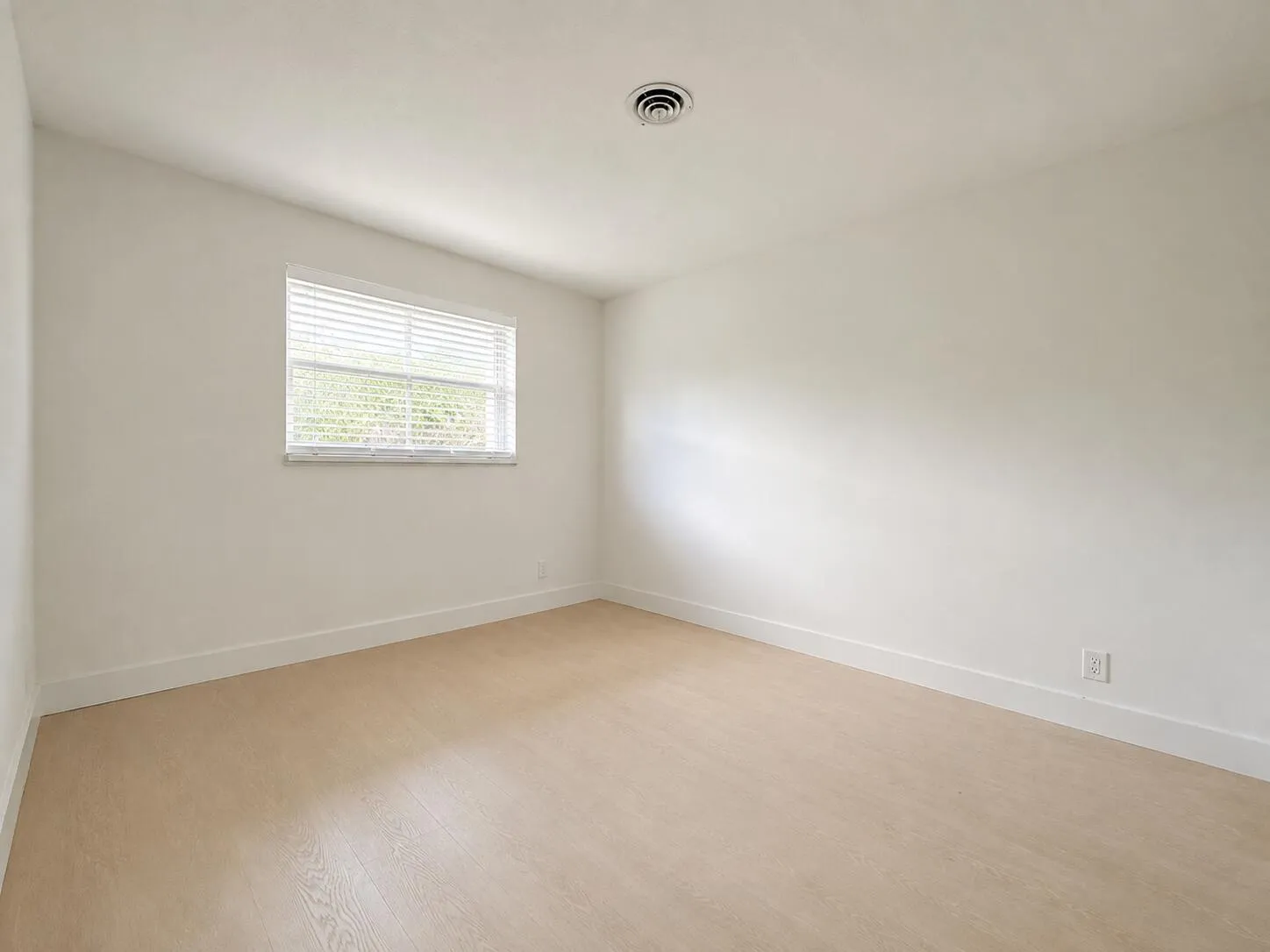 Neutral wall finishes with wood-finish flooring and a single window with blinds