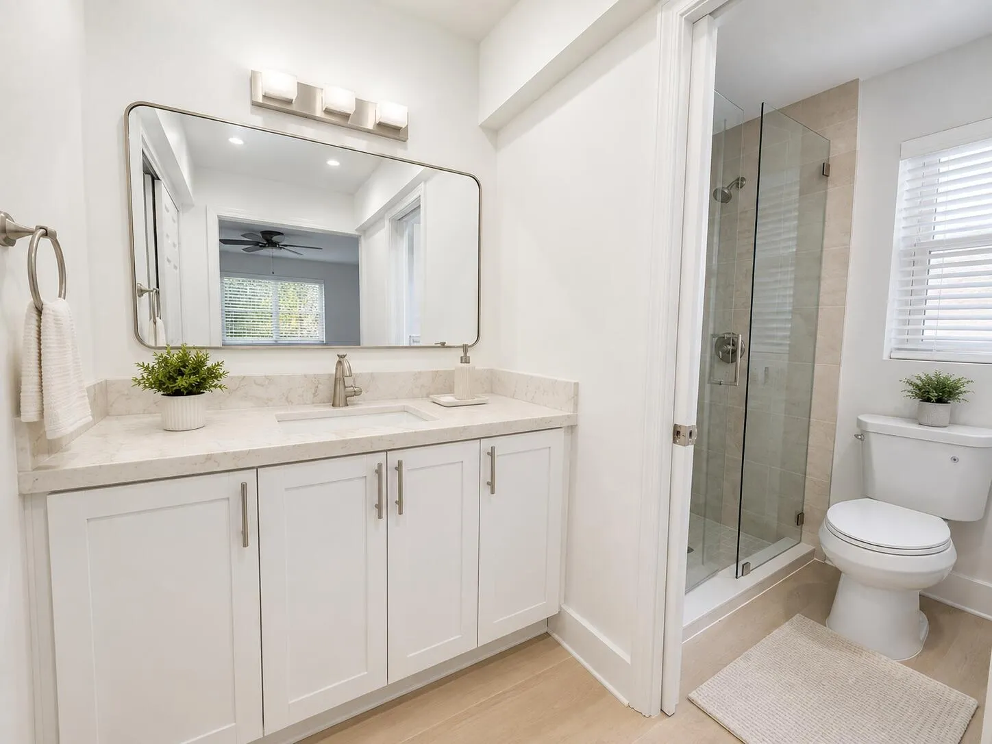 Bathroom featuring a white vanity with a stone countertop, an undermount sink, a framed mirror, and a glass-enclosed shower with tiled walls