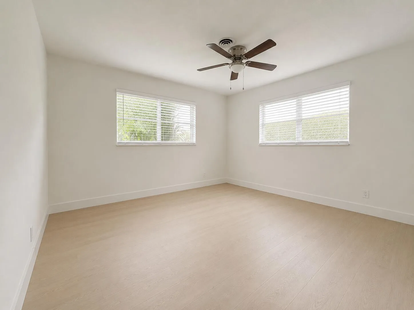 Recessed ceiling fan, two windows with blinds, wood-finish flooring, and white walls