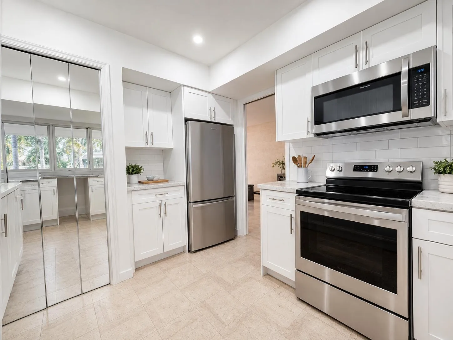 Kitchen featuring white shaker cabinetry, stainless steel appliances, light-toned tile flooring, white subway tile backsplash, and light-toned countertops