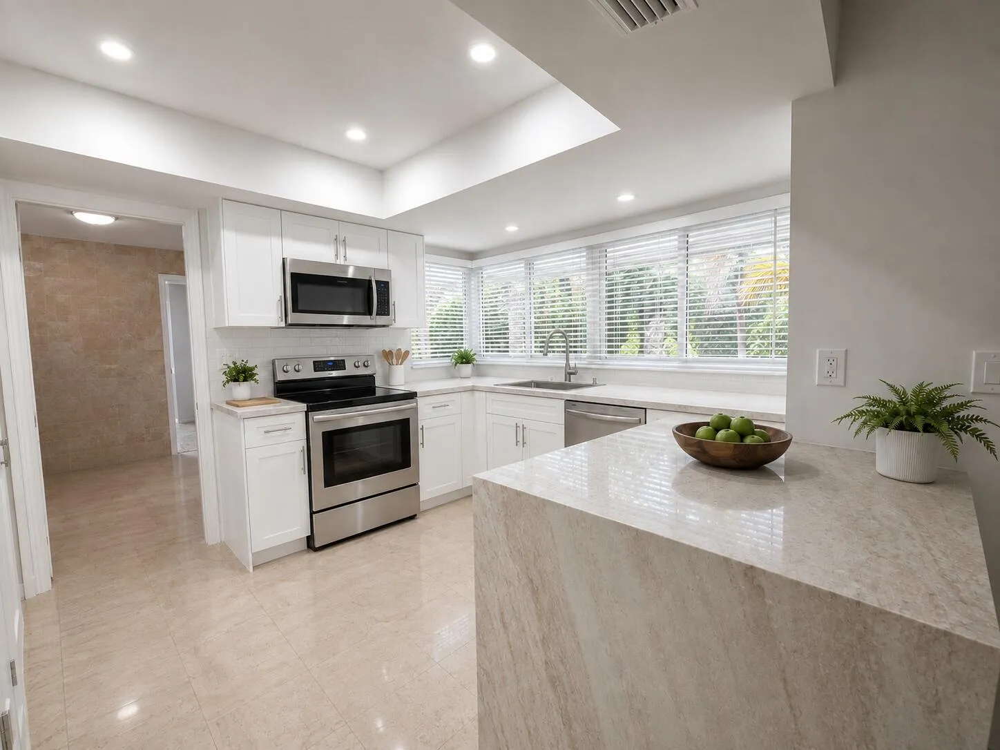 Modern kitchen featuring white cabinetry, stainless steel appliances, a breakfast bar, and multiple windows with blinds