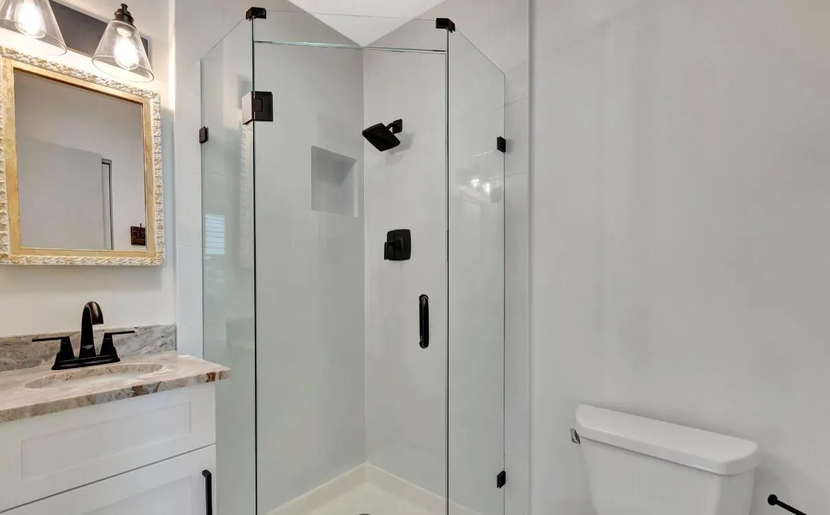 Glass-enclosed shower with matte black fixtures and built-in niche