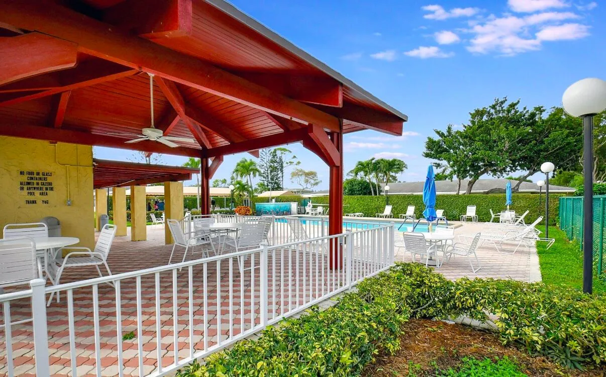 Covered patio with a ceiling fan, patterned paver flooring, and white railing