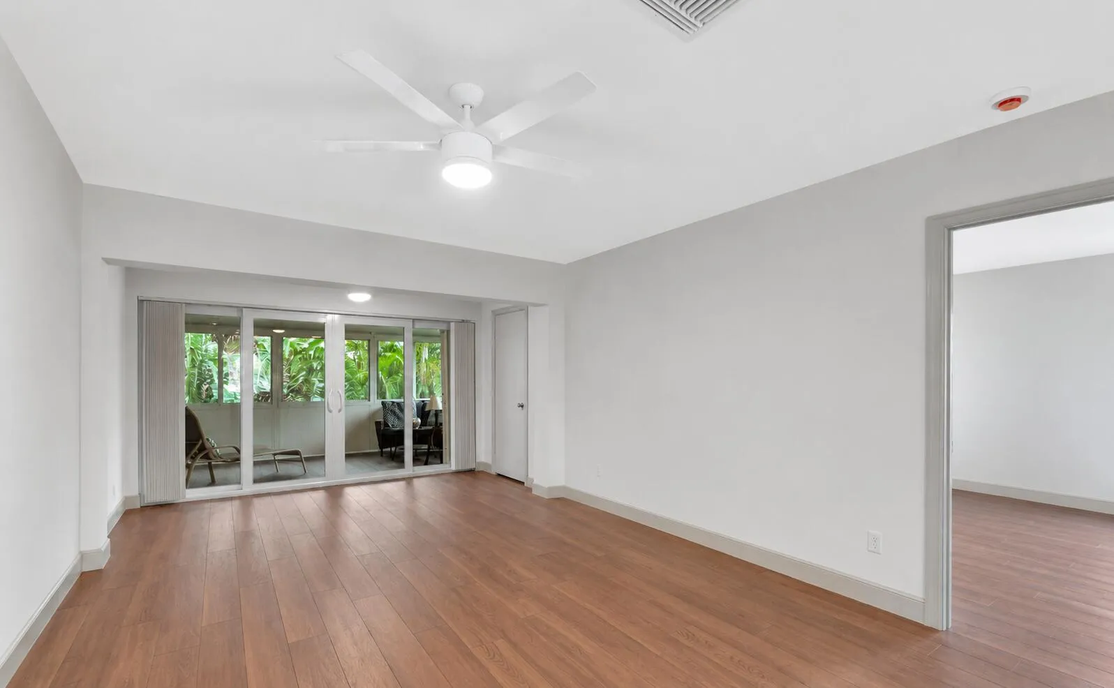 Wood-finish flooring, white walls, ceiling fan with integrated lighting, recessed lighting, and a glass sliding door leading to an outdoor space