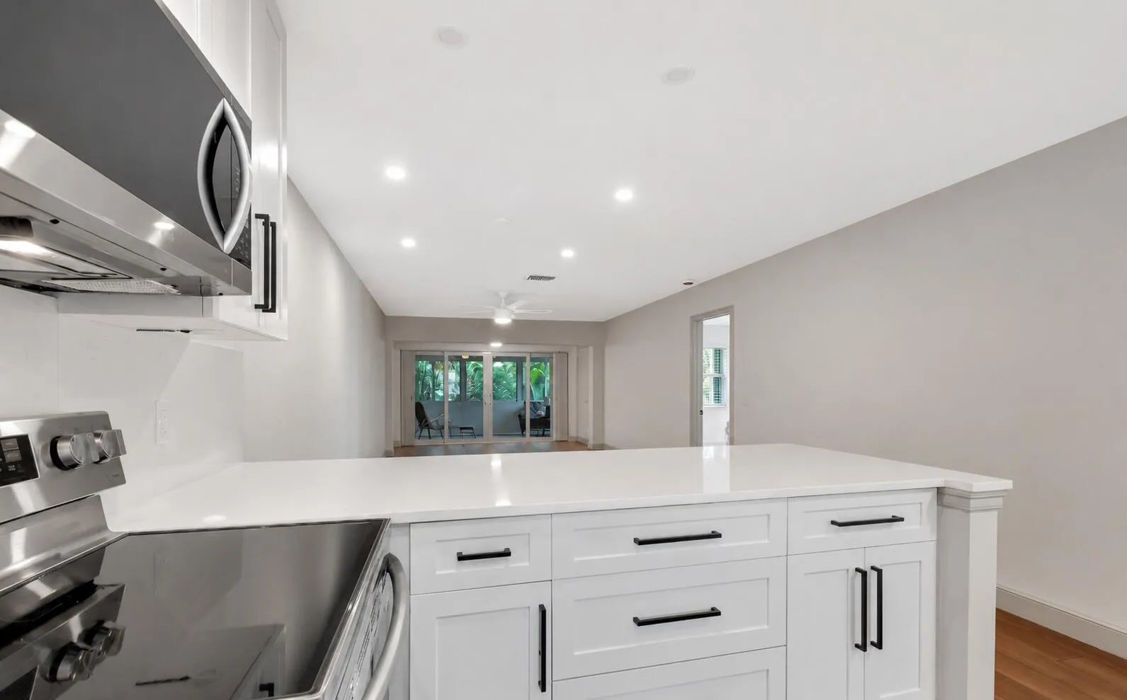 Kitchen featuring white cabinetry, stainless steel appliances, a white countertop, recessed lighting, and wood-finish flooring