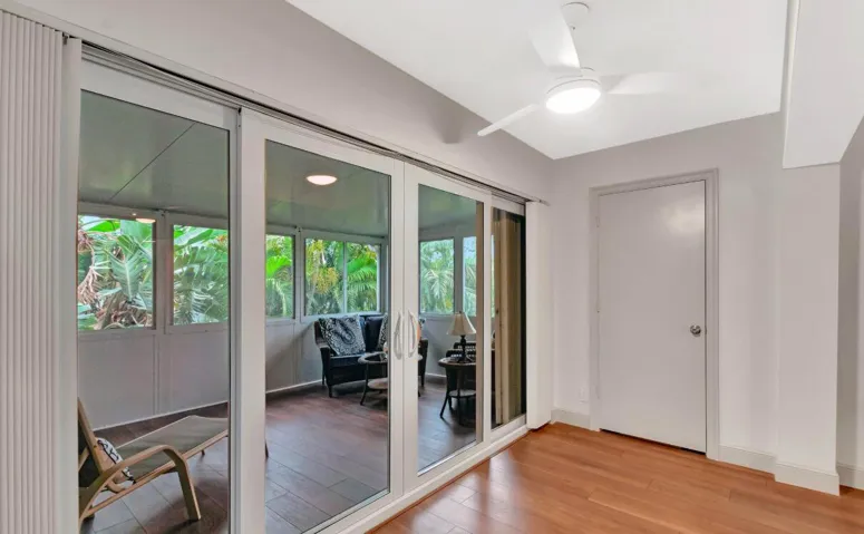 Wood-finish flooring, sliding glass doors, ceiling fan with integrated lighting, and a neutral wall palette