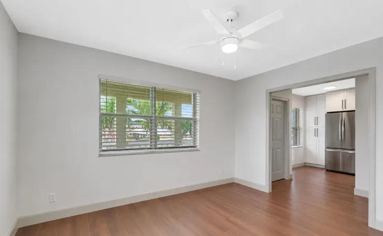 Wood-finish flooring, a ceiling fan, and a window with blinds