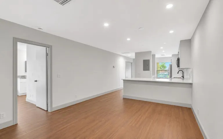 Open-concept living space featuring wood-finish flooring, recessed lighting, a kitchen island with a white countertop, and white cabinetry