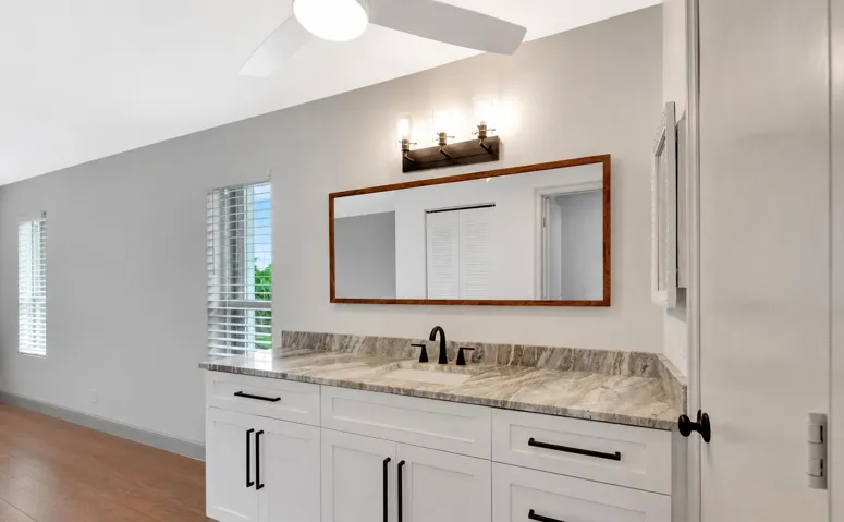 Vanity with a stone countertop, undermount sink, and matte black faucet